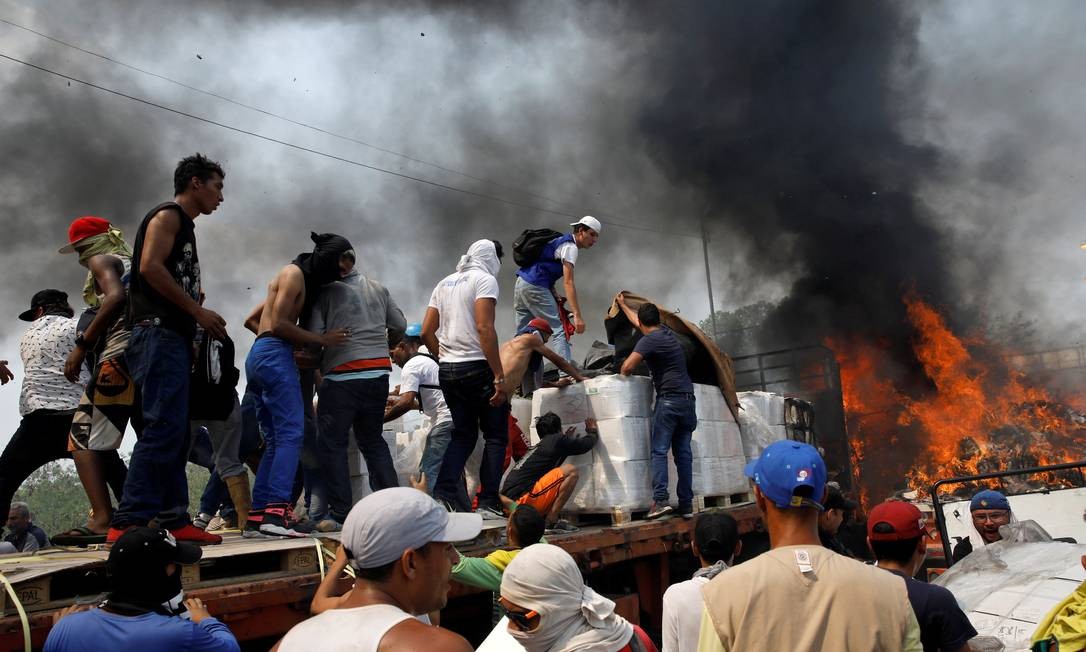 Voluntários tentam salvar produtos em caminhões de ajuda internacional incendiado por militares pró-Maduro em Cúcuta, na fronteira entre Colômbia e Venezuela Foto: MARCO BELLO / REUTERS