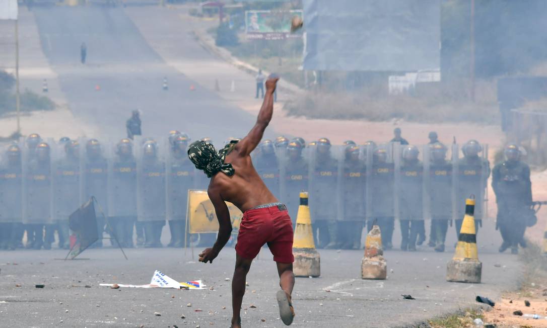 Manifestante atira pedras contra membros da Guarda Nacional Bolivariana da Venezuela na fronteira com o Brasil, em Pacaraima Foto: NELSON ALMEIDA / AFP