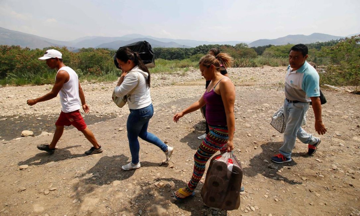 Venezuelanos caminham às margens do rio Táchira em Cúcuta, na Colômbia, após terem cruzado a fronteira; fim de semana é de tensão na divisa entre os dois países Foto: SCHNEYDER MENDOZA / AFP