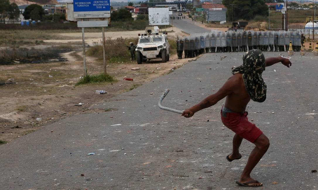 Homem lança objeto de metal contra agentes venezuelanos em Pacaraima, no estado brasileiro de Roraima; tentativas dea oposição venezuelana de levar carregamentos de ajuda humanitária do Brasil à Venezuela falharam nos primeiros dois dias Foto: BRUNO KELLY / REUTERS