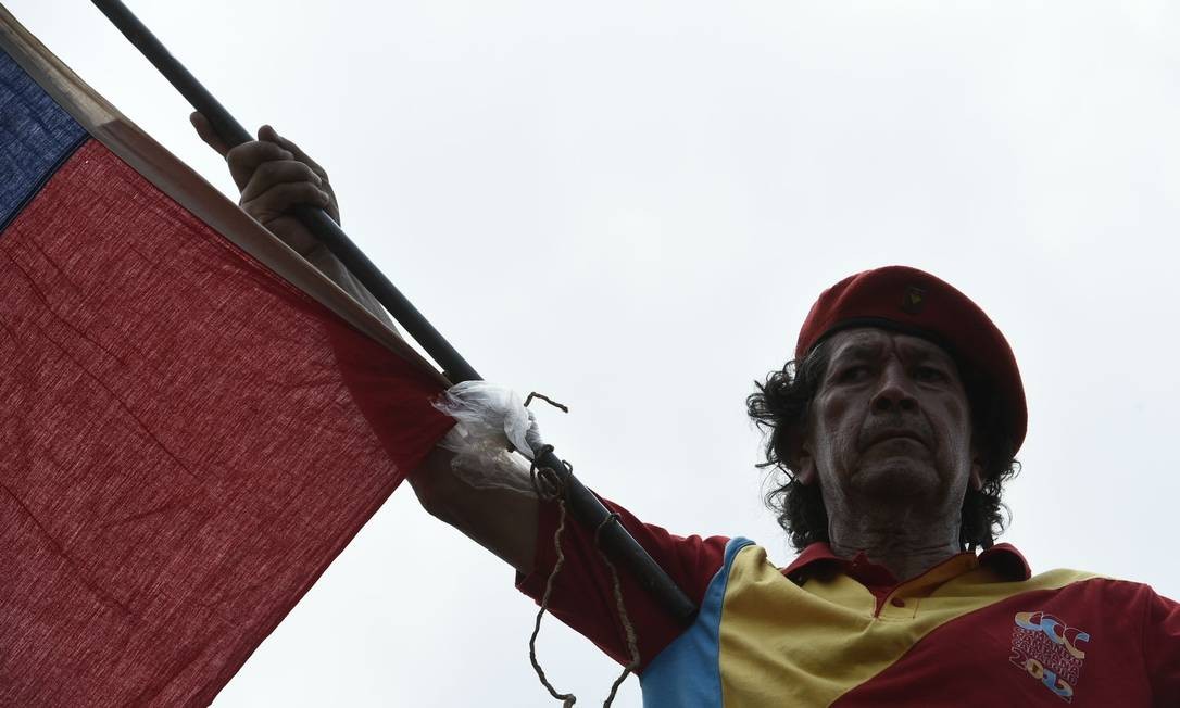 Apoiador do presidente Nicolás Maduro balança bandeira durante discurso de representantes do governo de Caracas no lado venezuelano da fronteira com a Colômbia; lá, mais de cem militares já desertaram Foto: FEDERICO PARRA / AFP
