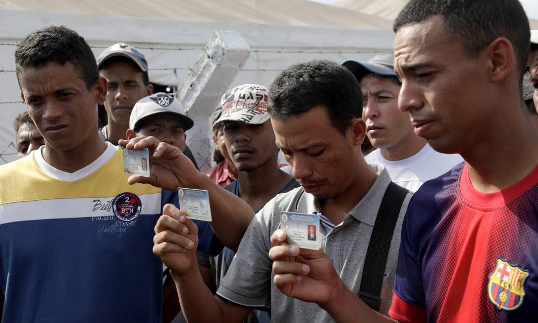 Membros da Guarda Nacional Bolivariana (GNB) mostram cartões de identidade militares após desertarem na fronteira com o Brasil Foto: RICARDO MORAES / REUTERS