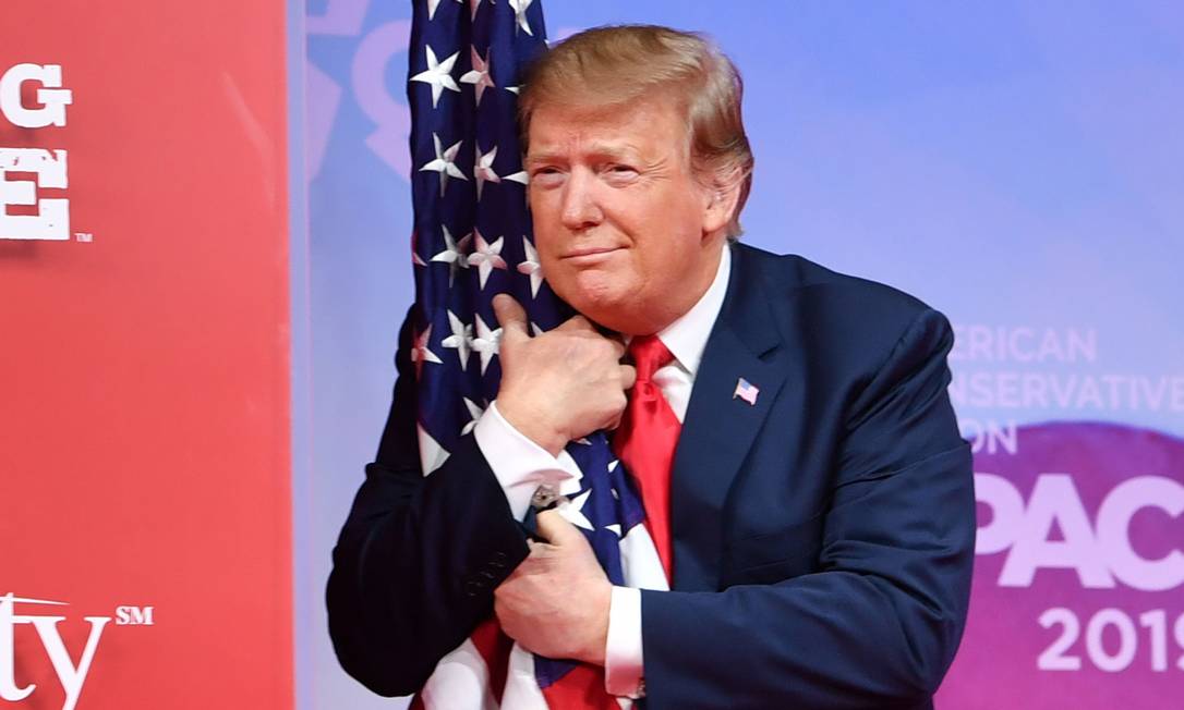 Presidente Donald Trump abraça bandeira americana na chegada à Conferência de Ação Política Conservadora (CPAC) Foto: NICHOLAS KAMM / AFP