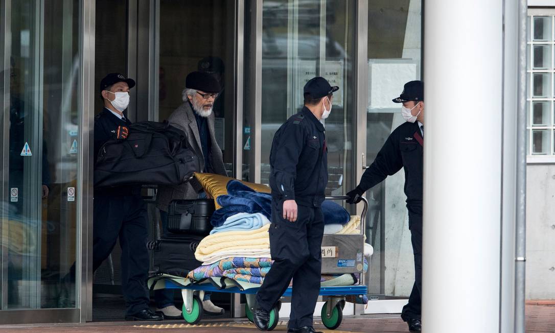 Before the release of the former Nissan executive, one of Carlos Goshen's lawyers, Takashi Takano (security guards) and security guards carry personal belongings Photo: Behroz Mehri / AFP