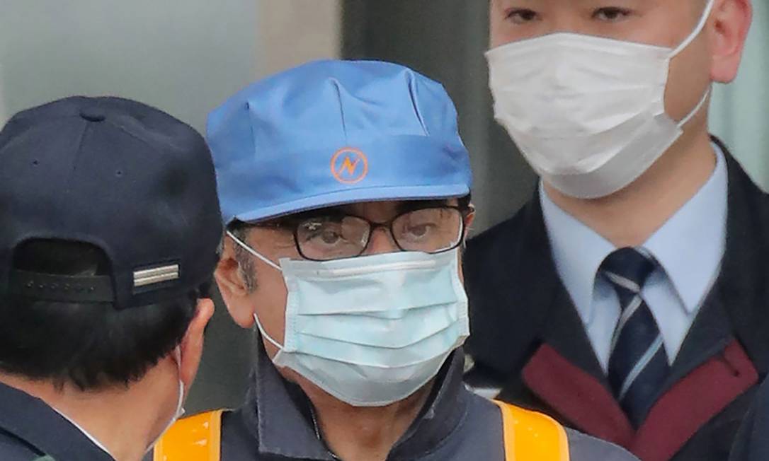 De boné azul e máscara cirúrgica, Ghosn deixa a prisão. Ele é acusado de fraude fiscal Foto: JIJI PRESS / AFP