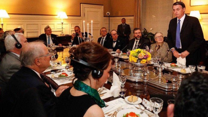 O escritor Olavo de Carvalho, à direita do presidente brasileiro, Jair Bolsonaro (de pé), durante jantar em Washington Foto: Divulgação