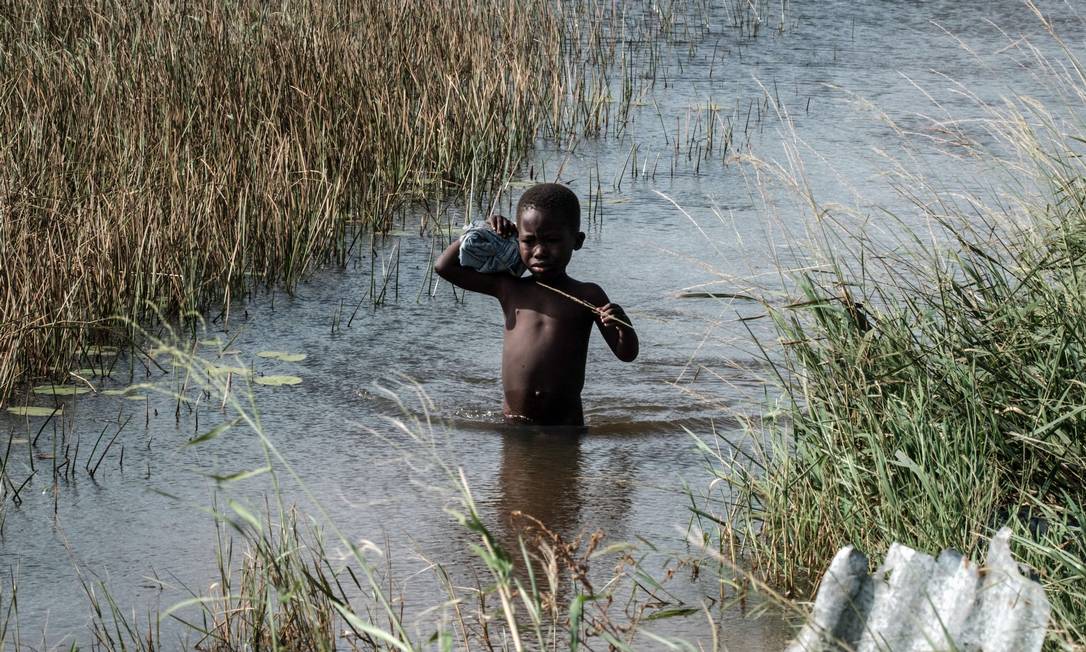 Criança passa por área inundada pelo ciclone Idai, em Beira, Moçambique Foto: YASUYOSHI CHIBA / AFP