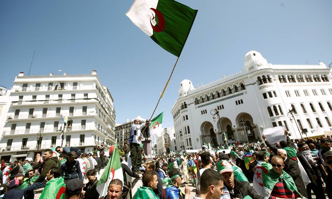Cerca de um milhÃ£o de pessoas tomaram as ruas de Argel, capital da ArgÃ©lia, para pedir a renÃºncia do presidente Abdelaziz Bouteflika. Na foto, um manifestante balanÃ§a a bandeira do paÃ­s em meio Ã  multidÃ£o Foto: RAMZI BOUDINA / REUTERS