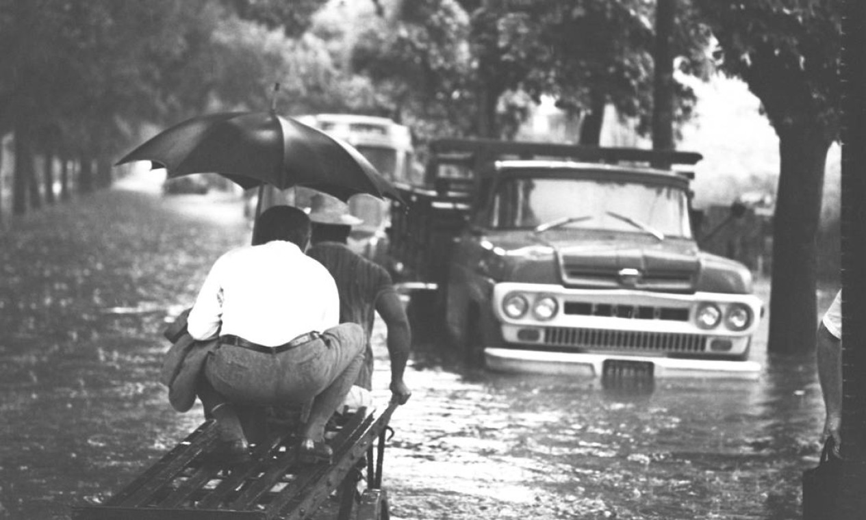 Homem sobe em carrinho de outro para escapar do alagamento na Rua Teodoro da Silva, Grajaú, Rio de Janeiro, em enchente de 1968 Foto: Agência O Globo
