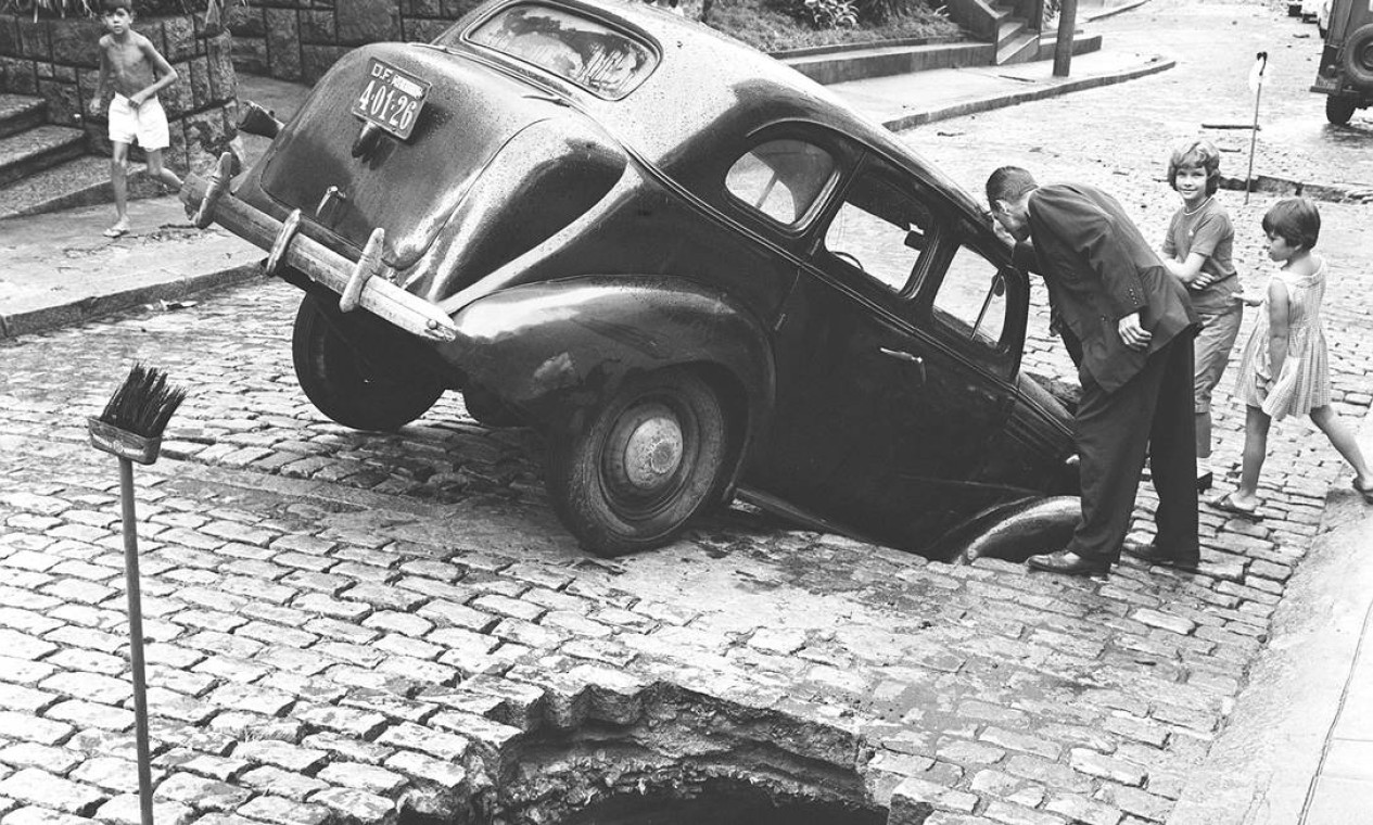 Carro preso em buraco na rua, aberto pela enchente em 1962, no Rio de Janeiro Foto: Agência O Globo