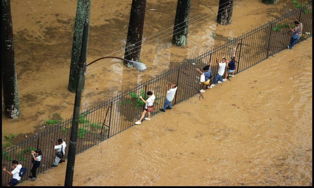 Pedestres são obrigados a usar as grades do Jardim Botânico, em 1996 para escapar da água que cobriu a rua com nome do bairro Foto: Márcia Foletto / Agência O Globo