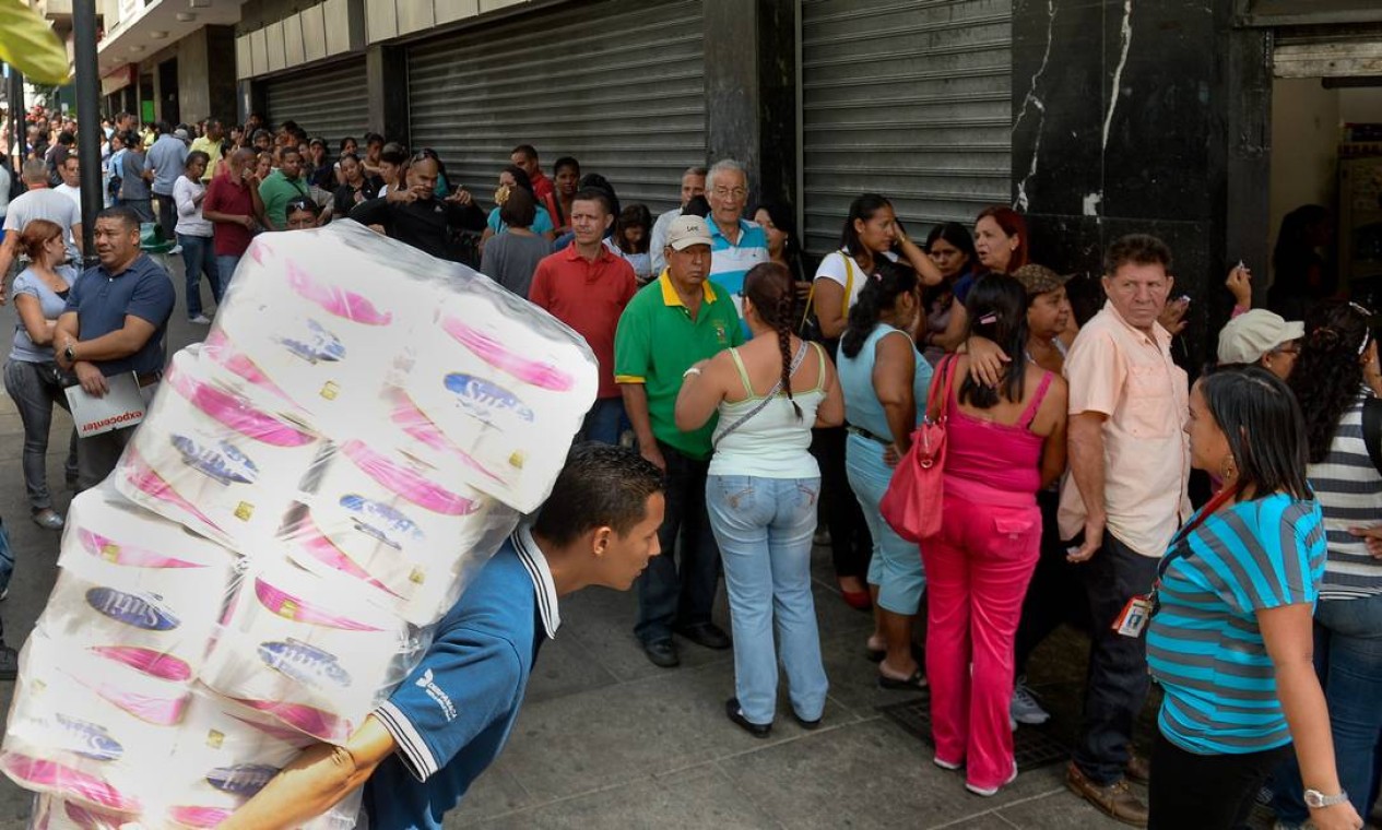 Em foto de 2016, venezuelanos formam longa fila para comprar produtos básicos nos mercados; é normal precisar ir a vários estabelecimentos para encontrar alimentos e itens de higiene Foto: FEDERICO PARRA / AFP