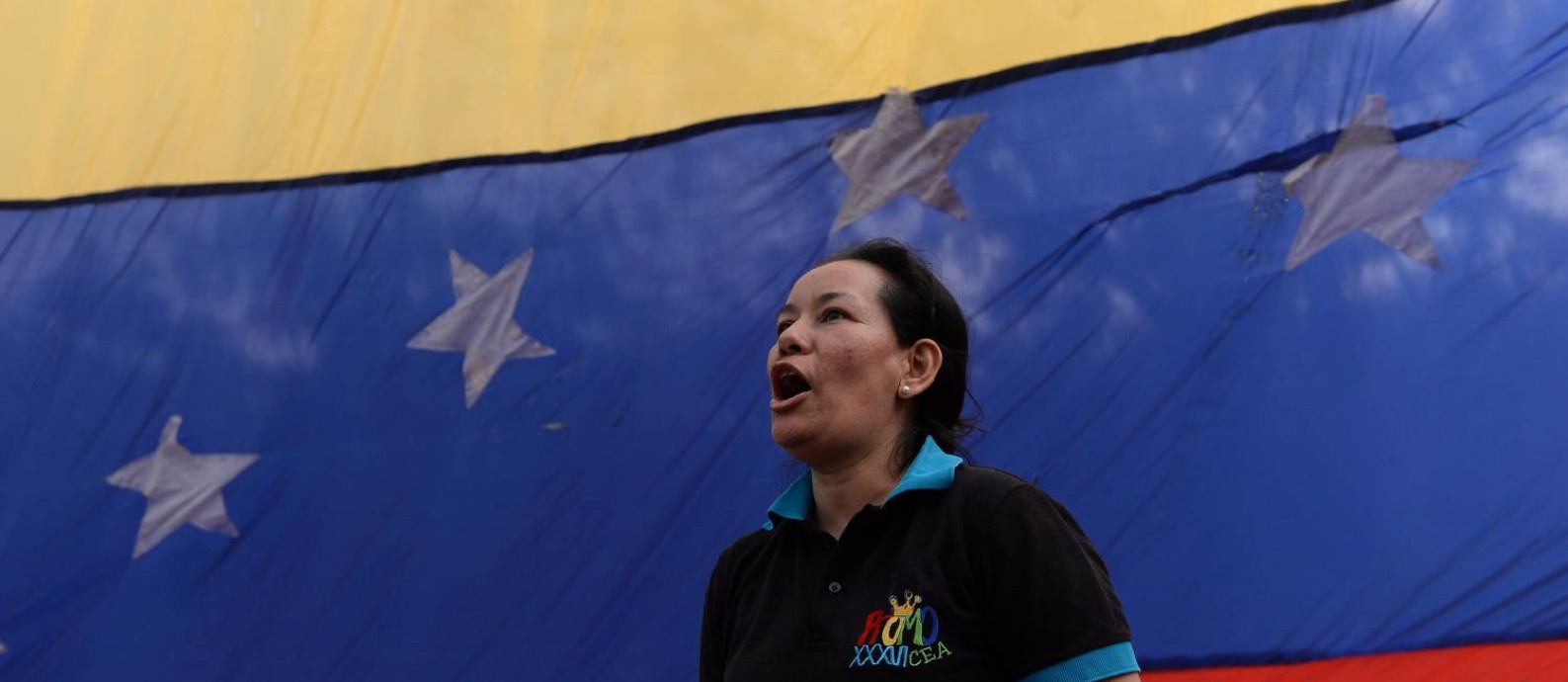 Mulher em frente à bandeira da Venezuela durante manifestação em Caracas; clima político é tenso no país sul-americano Foto: FEDERICO PARRA / AFP