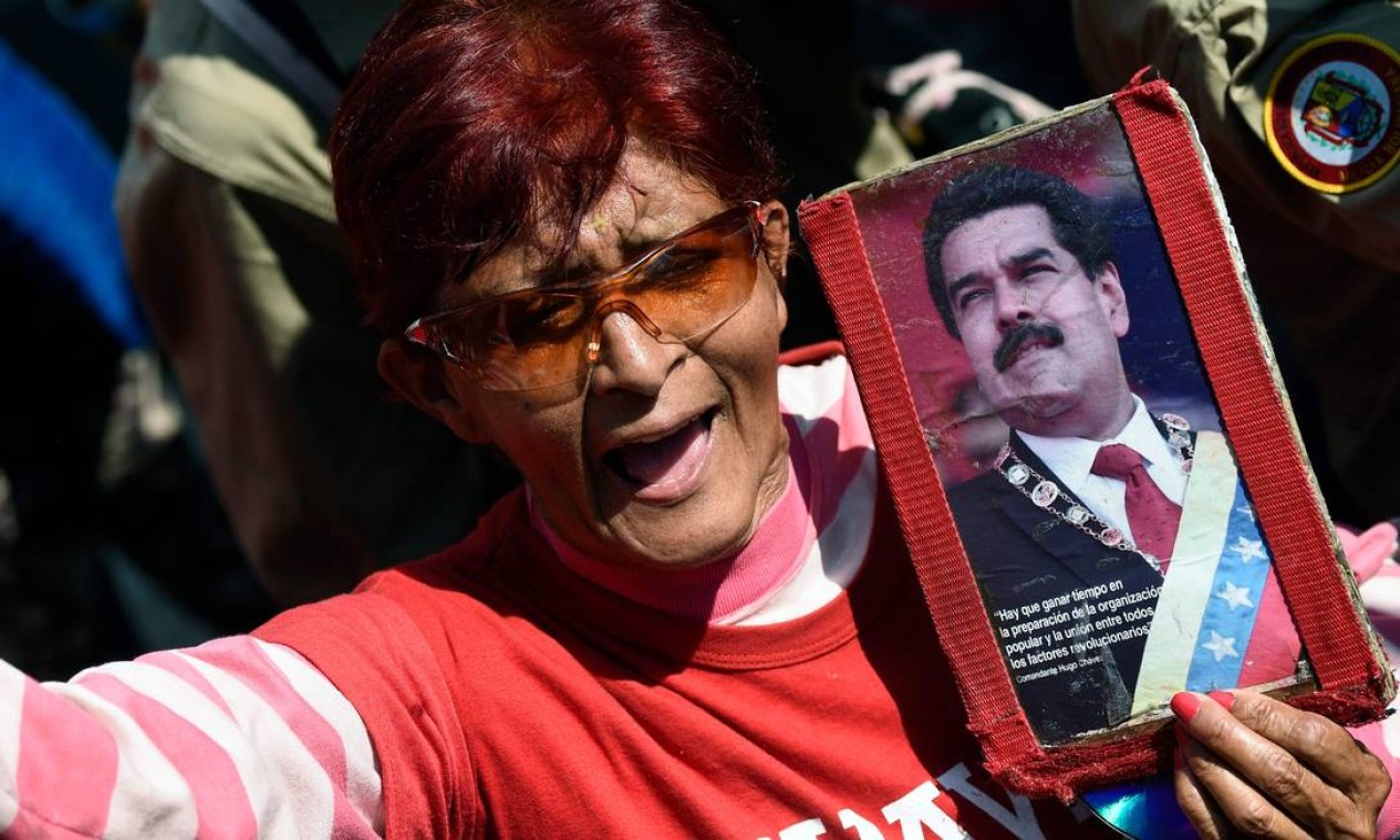 Mulher segura retrato de Nicolás Maduro para mostrar seu apoio ao presidente em Caracas Foto: FEDERICO PARRA / AFP