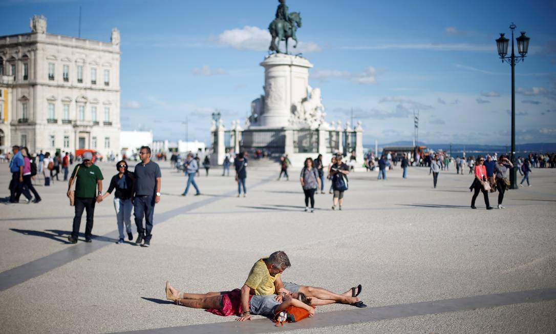 Casal de turistas descansa na Praça do Comércio, o coração de Lisboa Foto: Rafael Marchante / Agência O Globo