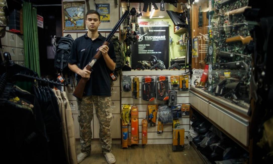 O vendedor Caio Queiroz exibe armas disponíveis para venda na loja Tucunará, em Brasília. Segundo ele, ligações de interessados se tornaram mais frequentes Foto: Daniel Marenco / Agência O Globo