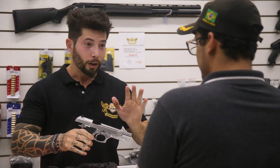 O empresário Axl Satier, 37 anos, que administra uma rede com três pontos de venda no Estado do Rio, atende cliente interessado em comprar uma arma em uma de suas lojas Foto: Marcelo Regua / Agência O Globo