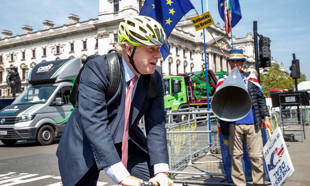 
O ex-chanceler Boris Johnson chega ao Parlamento de bicicleta, em Londres, diante de um manifestante favorável à permanência do Reino Unido na UE: para críticos, um ‘bufão’, mas é um dos favoritos a suceder May
Foto:
/
Tolga AKMEN/AFP/15-05-2019
