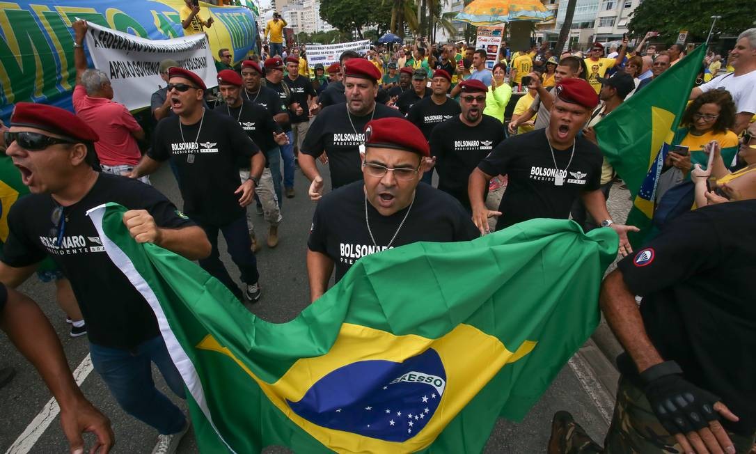 Homens de boinas vermelhas carregam a bandeira do Brasil, em Copacabana Foto: Marcelo Regua / Agência O Globo