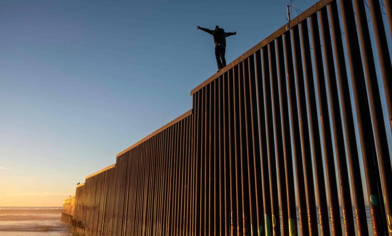 Migrantes hondurenho escalou muro entre EUA e México Foto: GUILLERMO ARIAS / AFP
