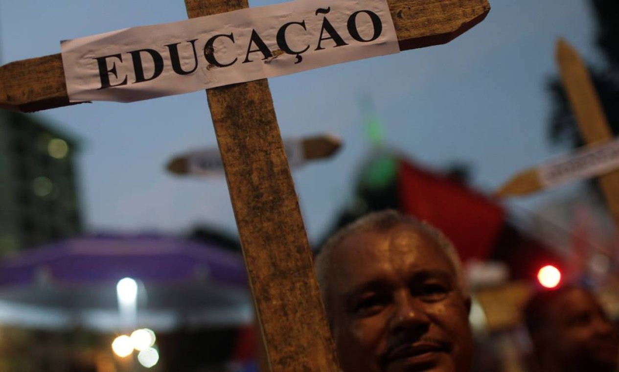 Um homem segura uma cruz com a placa "Educação" durante um protesto de estudantes contra cortes nos gastos federais no setor planejados pelo governo Bolsonaro Foto: RICARDO MORAES / REUTERS