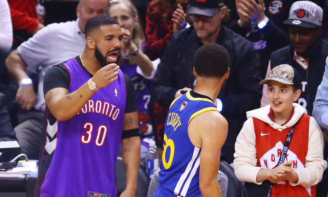 Drake batendo boca com o jogador Stephen Curry, do Golden State Warriors, durante o jogo contra o Toronto Foto: Vaughn Ridley / AFP