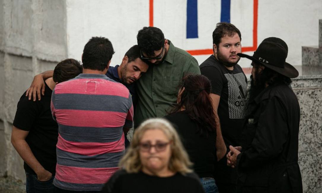 O namorado de Marcela é abraçado por amigos durante o enterro da jovem Foto: Brenno Carvalho / Agência O Globo