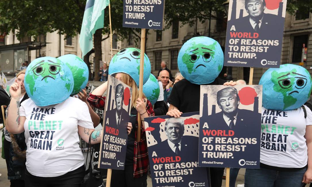 Ativistas ambientais vestem máscara de planeta Terra chateado e carregam cartazes que diz "Um mundo de razões para resistir a Trump" Foto: ISABEL INFANTES / AFP