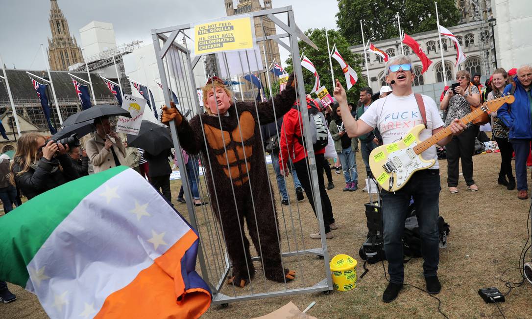 Homem protesta dentro de jaula com máscara de Trump e roupa de macaco Foto: ALKIS KONSTANTINIDIS / REUTERS