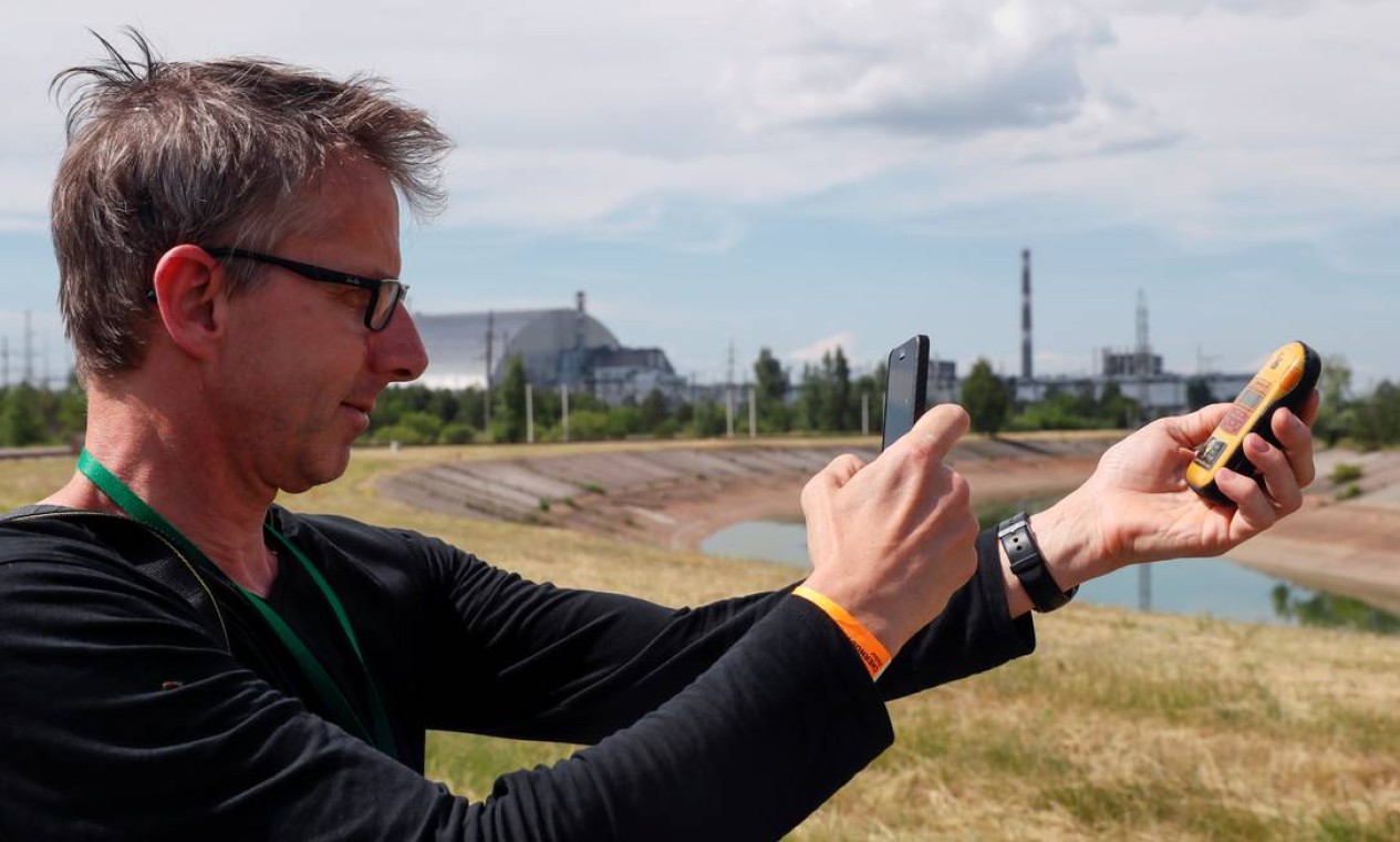 Turista mede níveis de radioatividade perto do sarcófago que cobre o reator 4 da Usina de Chernobyl Foto: VALENTYN OGIRENKO / REUTERS