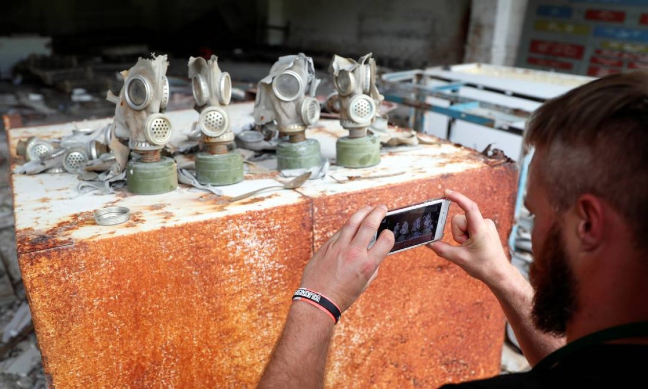 Turista fotografa máscaras de gás numa antiga base soviética perto da Usina de Chernobyl, em 2 de junho de 2019. A visitação aumentou cerca de 40% após o sucesso da série da HBO Foto: VALENTYN OGIRENKO / REUTERS