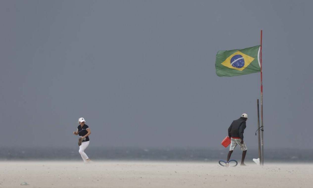 Vento, ventania: mulher corre na areia de Copacabana Foto: Domingos Peixoto / Agência O Globo