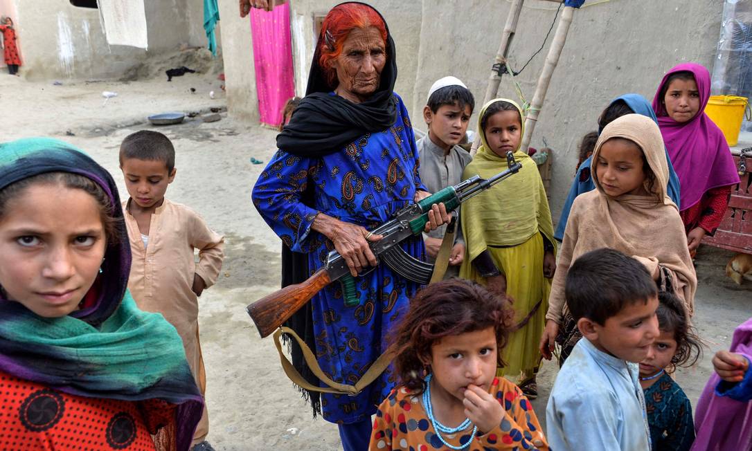 Mulher afegã leva fuzil para proteger crianças no caminho até a escola. O Afeganistão foi apontado como o país menos pacífico do mundo pelo estudo do Instituto para Economia e Paz. Quase 18 anos depois do início da guerra, o país vive um aumento na violência, no terrorismo e na instabilidade política Foto: NOORULLAH SHIRZADA / AFP