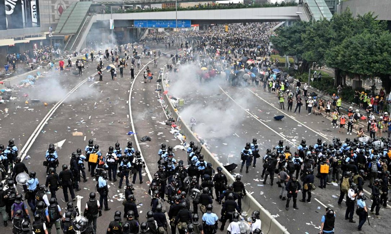 Manifestantes reagem após a polícia ter disparado gás lacrimogêneo durante uma manifestação contra uma polêmica proposta de lei de extradição em Hong Kong. Pela primeira vez em pelo menos duas décadas, a polícia usou balas revestidas com borracha Foto: ANTHONY WALLACE / AFP