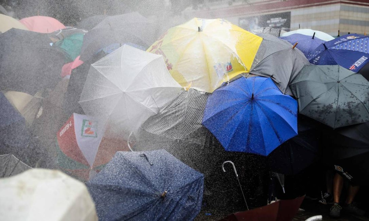 Manifestantes se protegem com guarda-chuvas contra spray de pimenta usado pela polícia durante a manifestação Foto: DALE DE LA REY / AFP