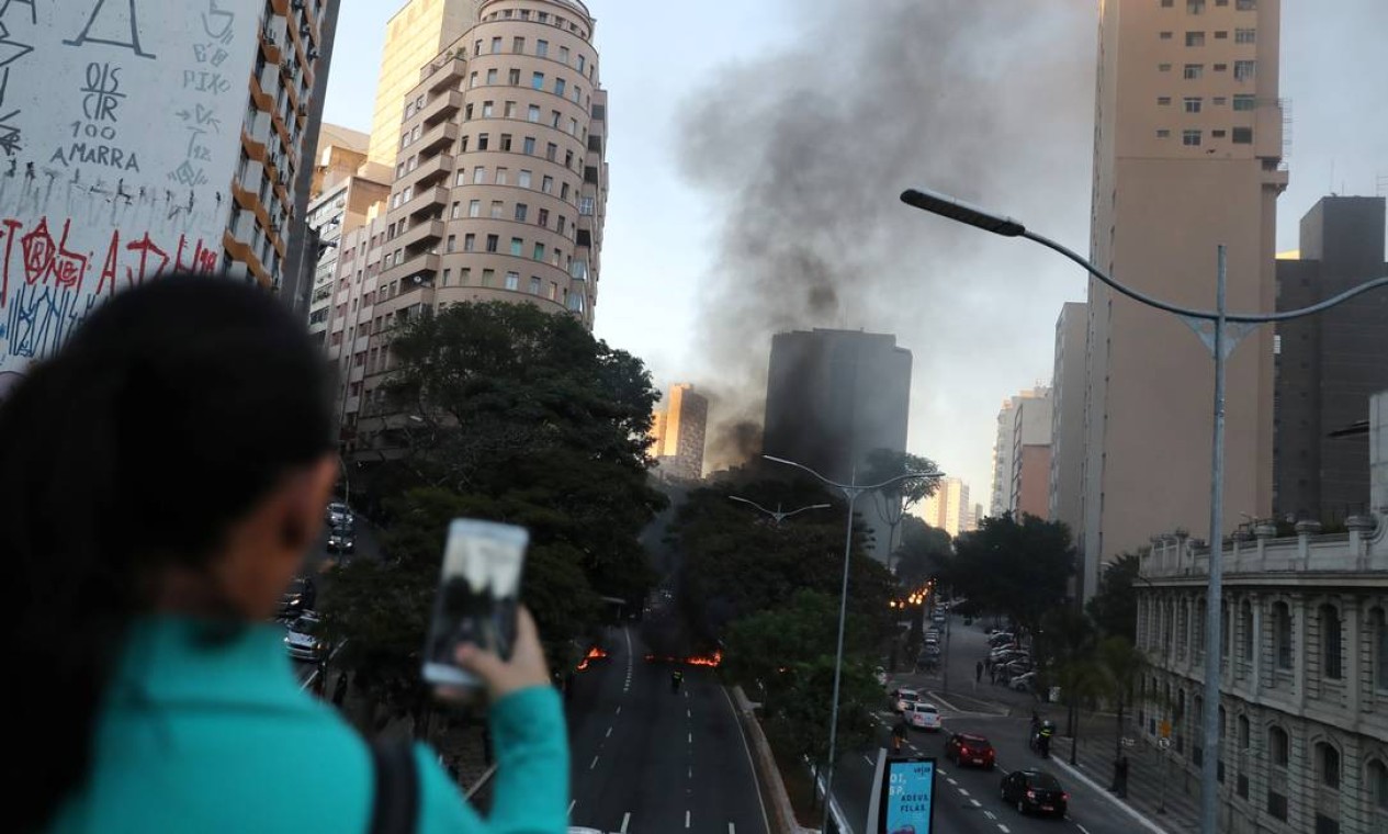 Uma mulher tira foto de pneus queimando no centro de São Paulo Foto: NACHO DOCE / Reuters