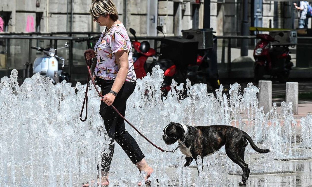 TOPSHOT - A woman walks her dog through a fountain installation in the French eastern city of Lyon on June 24, 2019 as temperatures soar to 35 degrees Celsius. - Fans flew off store shelves and public fountains offered relief from the heat as temperatures soared in Europe on Monday, with officials urging vigilance ahead of even hotter conditions forecast later in the week. Meteorologists blamed a blast of torrid air from the Sahara for the unusually early summer heatwave, which could send thermometers up to 40 degrees Celsius (104 Fahrenheit) across large swathes of the continent. (Photo by PHILIPPE DESMAZES / AFP) Foto: PHILIPPE DESMAZES / AFP