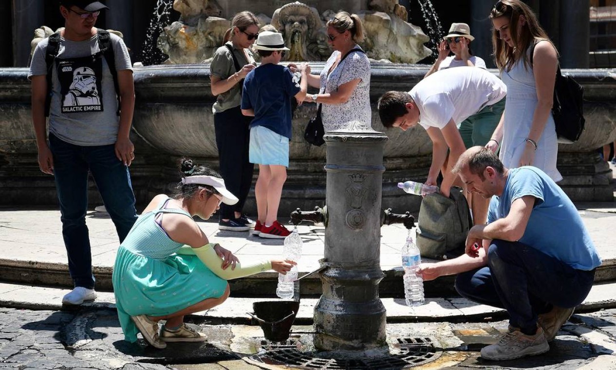 Os turistas bebem água e recarregam garrafas em uma fonte pública para se refrescar durante a onda de calor, em Roma Foto: ALBERTO PIZZOLI / AFP