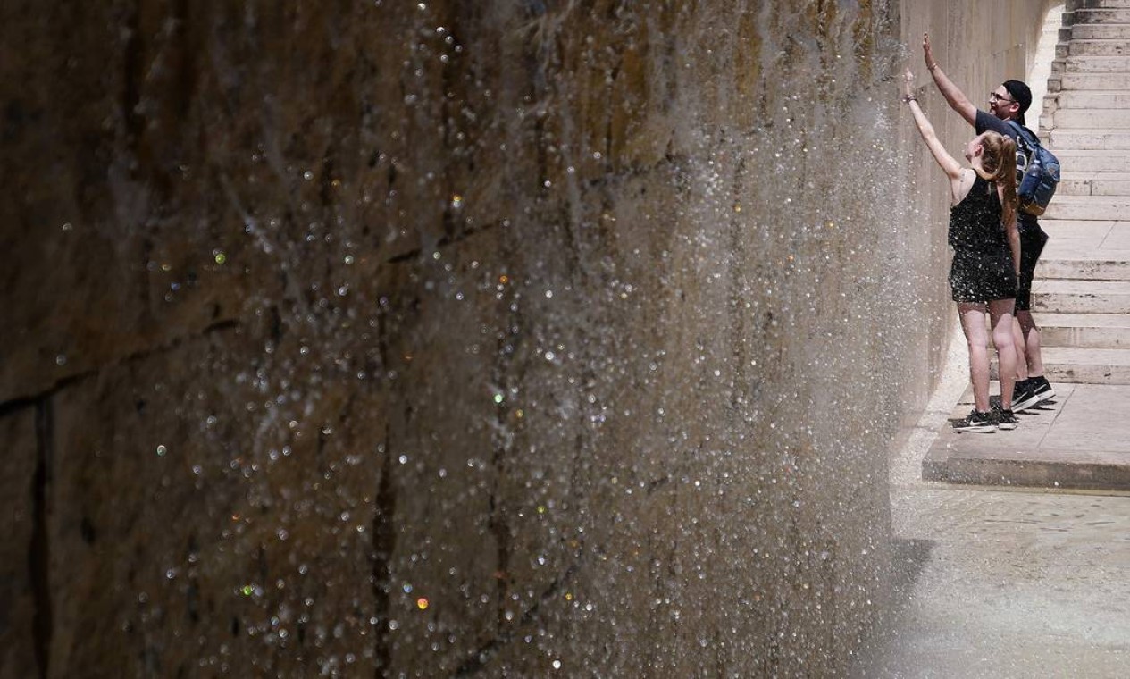Pessoas se refrescam em uma fonte em formato de cachoeira durante uma onda de calor excepcional para o início do verão, em 24 de junho de 2019 em Roma Foto: ALBERTO PIZZOLI / AFP