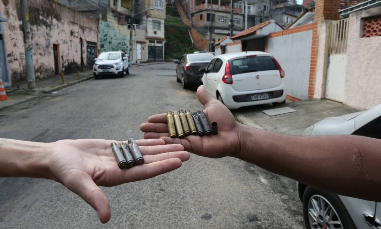 Moradores mostram cápsulas achadas na rua depois do tiroteio Foto: Marcia Foletto / Agência O Globo