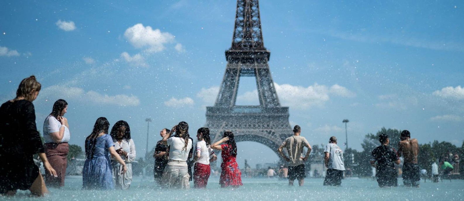 Pessoas se resfrescam na fonte da esplanada do Trocadero, em Paris. Foto: KENZO TRIBOUILLARD / AFP