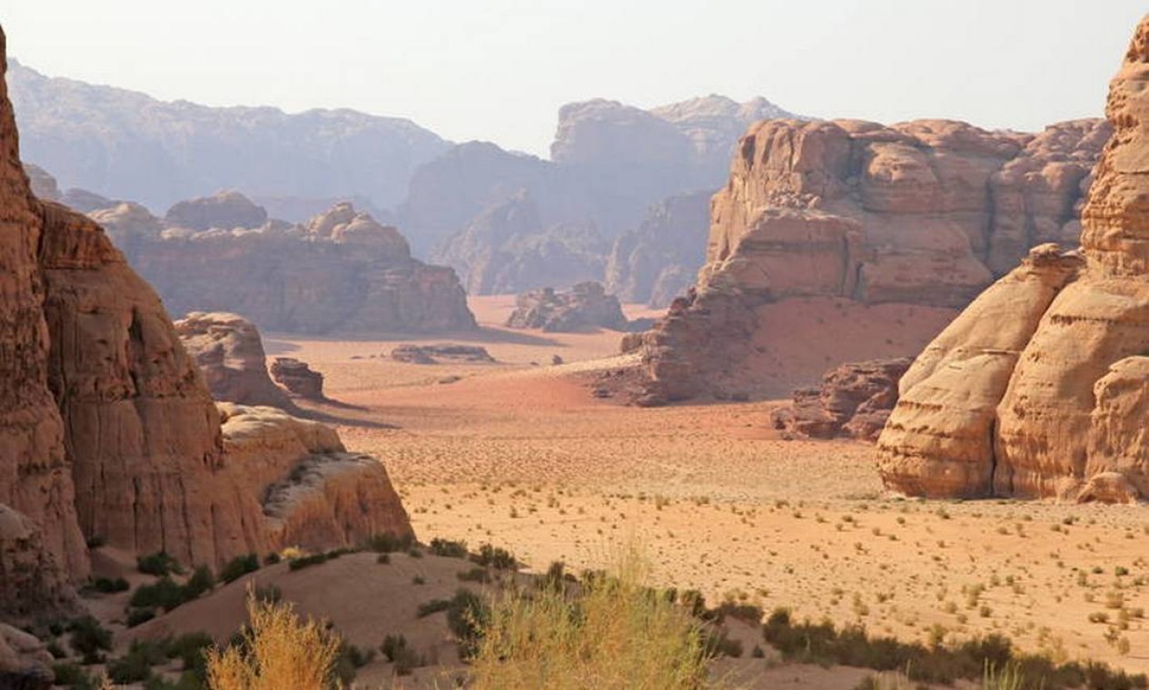 Ao Sul da Jordânia, a Área de Wadi Rum, possui uma paisagem variada do deserto, com uma variedade de desfiladeiros estreitos, arcos naturais, imponentes falésias, rampas, deslizamentos de terra e cavernas. Gravuras rupestres, inscrições e restos arqueológicos no local testemunham 12.000 anos de ocupação humana e interação com o ambiente natural. A combinação de 25.000 gravuras rupestres com 20.000 inscrições traça a evolução do pensamento humano e o desenvolvimento inicial do alfabeto. O local ilustra a evolução da atividade pastoril, agrícola e urbana na região Foto: Reprodução