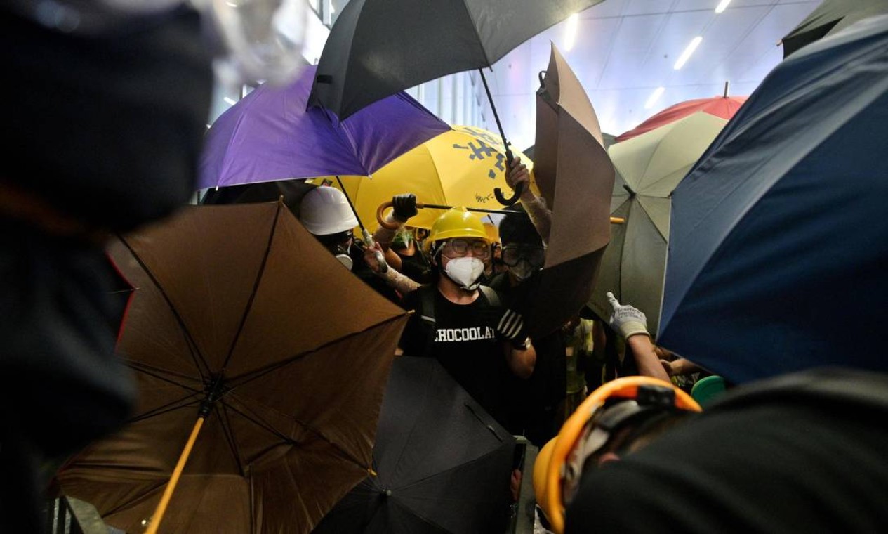 Manifestantes com guarda-chuvas, símbolos dos protestos que tomaram conta da cidade em 2014 e exigiam o direito de escolher o governante do território em votação Foto: ANTHONY WALLACE / AFP