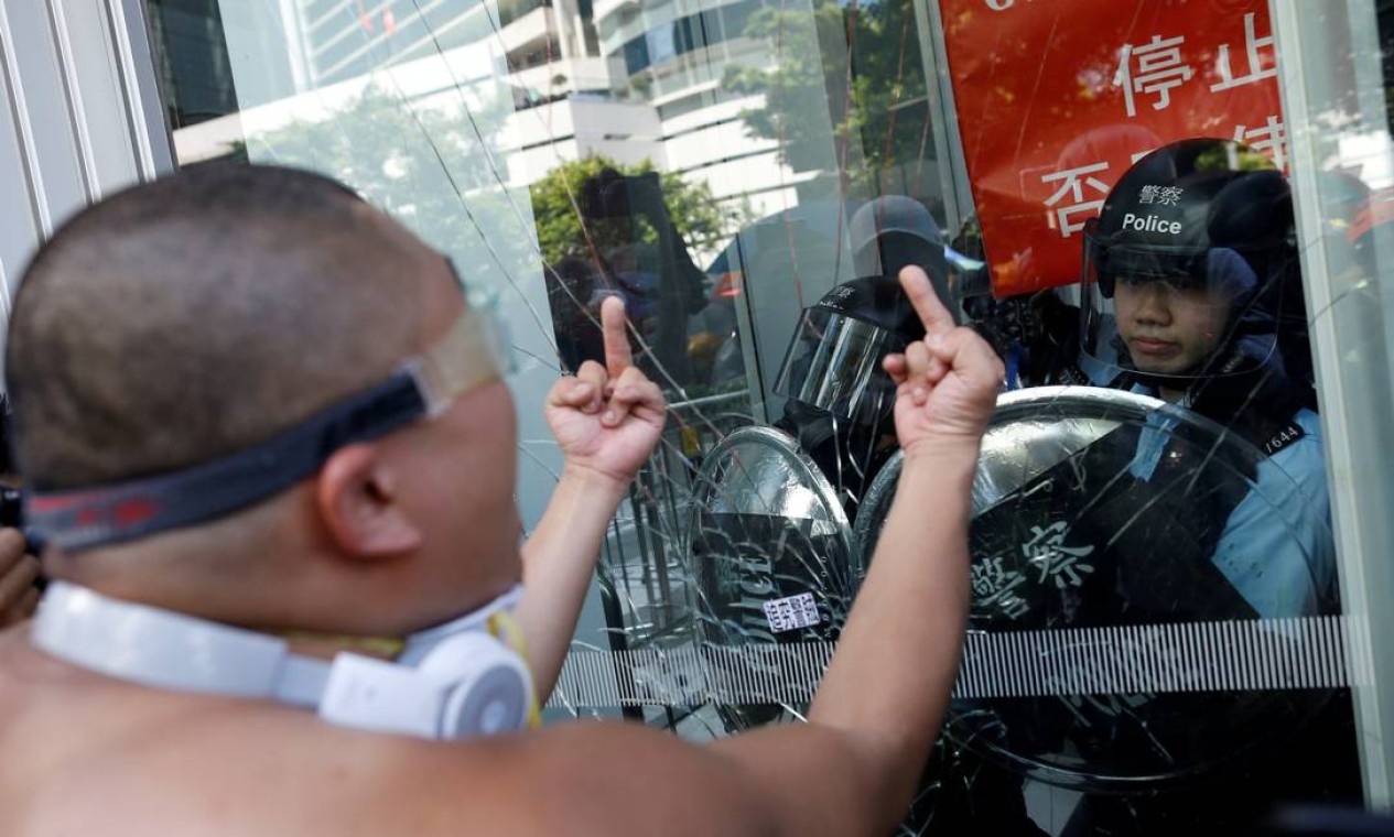 Manifestante faz gesto obsceno para policial que protegia prédio do governo Foto: THOMAS PETER / REUTERS