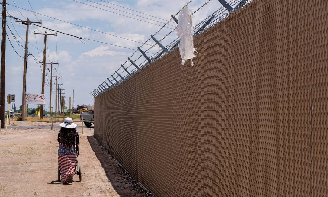 Mulher caminha ao lado de uma cerca perto de abrigo da Patrulha da Fronteira, em Clint Foto: LUKE MONTAVON / AFP