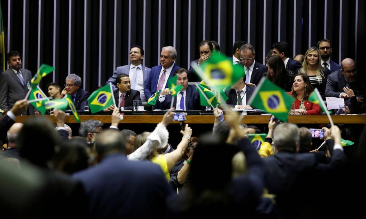 O presidente da Câmara dos Deputados, Rodrigo Maia, é visto entre bandeiras do Brasil levantandas por apoiadores do governo e da reforma da Previdência que será votada nesta quarta-feira, no plenário da Casa Foto: ADRIANO MACHADO / REUTERS