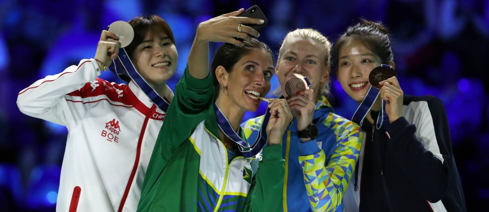 Hora da selfie: Nathalie Mollenhausen entre a chinesa Lin Sheng, medalha de prata, e as medalhistas de bronze Olena Kryvytska, da Ucrânia, e Vivian Kong Man Wai, de Hong Kong, no pódio do Mundial de Esgrima de Budapeste Foto: PETER KOHALMI / AFP