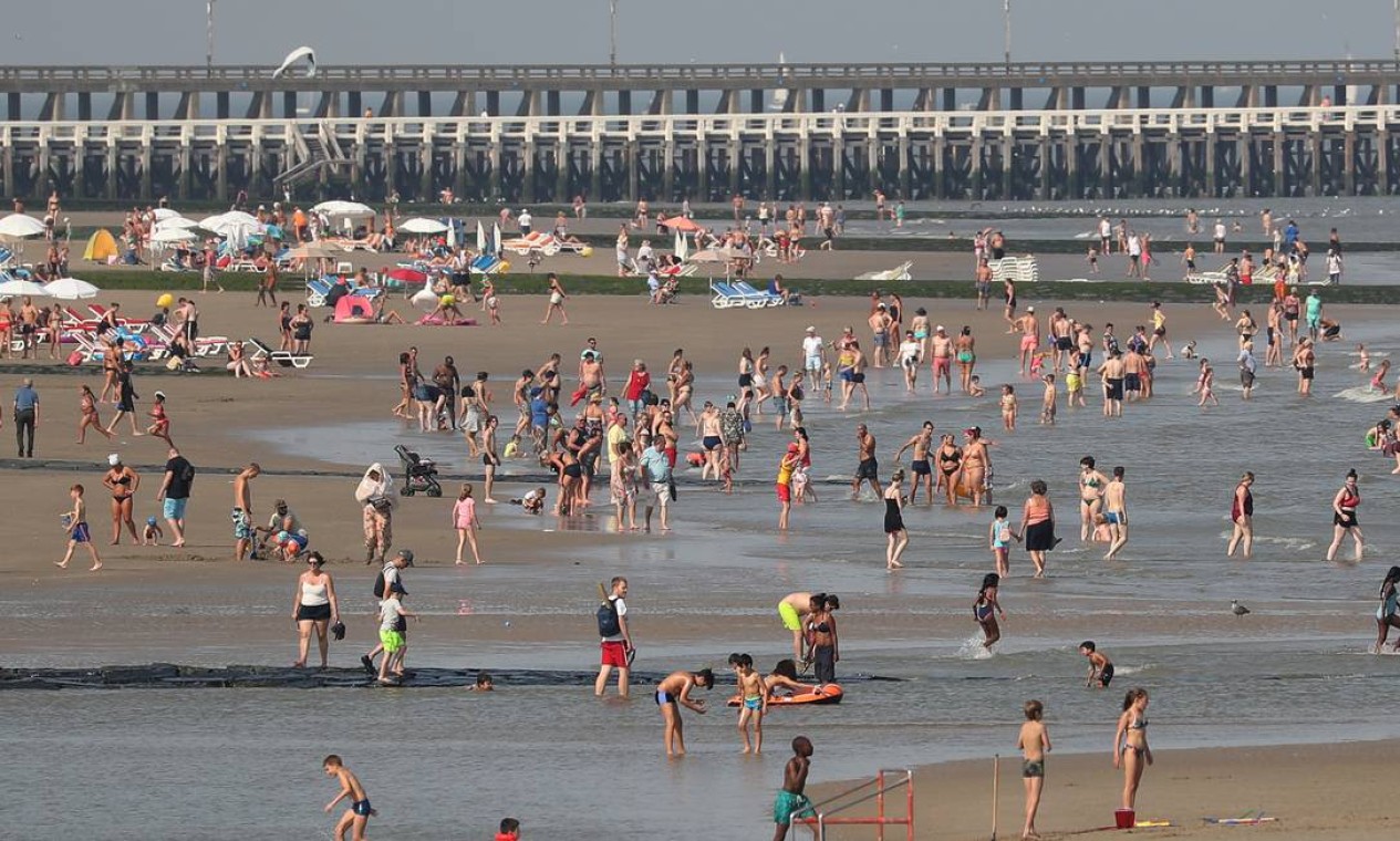 Pessoas aproveitam o calor na praia na cidade de Blankenberge, Bélgica. Ao longo do ano, em geral, a temperatura na cidade varia de 2°C a 21°C no verão e raramente é inferior a -4°C ou superior a 25°C, de acordo com o site Weather Spark Foto: YVES HERMAN / REUTERS