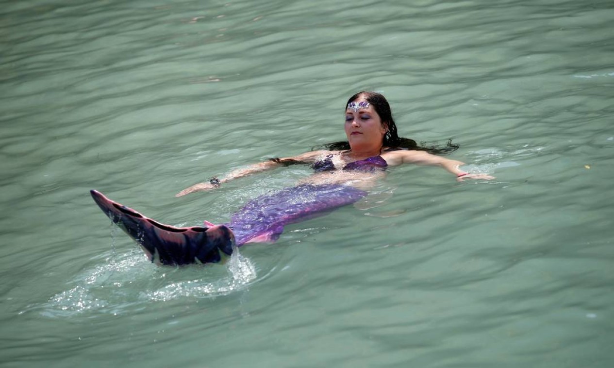 Uma mulher vestida como uma sereia nada nas águas do rio Soca, em Tolmin, Eslovênia, Foto: BORUT ZIVULOVIC / REUTERS