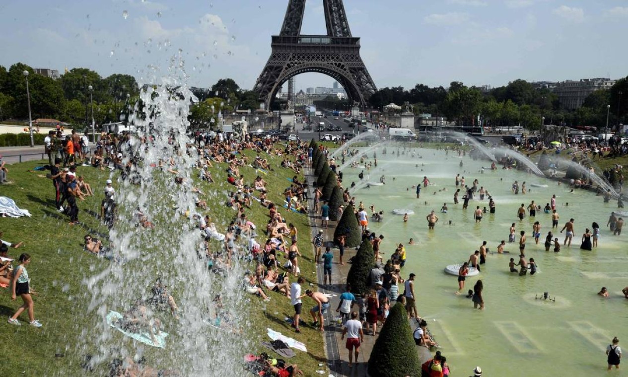 Pessoas se refrescam e tomam sol nas fontes do Trocadéro, ao lado da Torre Eiffel, em Paris, quando uma onda de calor atinge a capital francesa. Depois que todos os recordes de temperaturas foram batidos na Bélgica, Alemanha e Holanda ontem, Grã-Bretanha e Paris também experimentam as temperaturas mais altas de todos os tempos Foto: BERTRAND GUAY / AFP